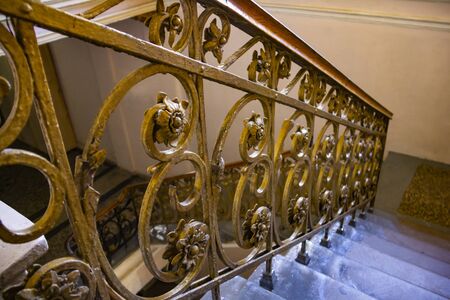 An old stairs with gold metal banister in empty building.の写真素材