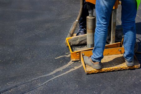 Builder worker with cut-off machine is drilling new asphalt to check it.の写真素材