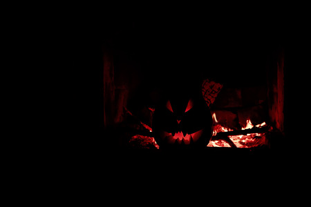 Halloween creepy pumpkin fireplace with fire, isolated in the darkの写真素材