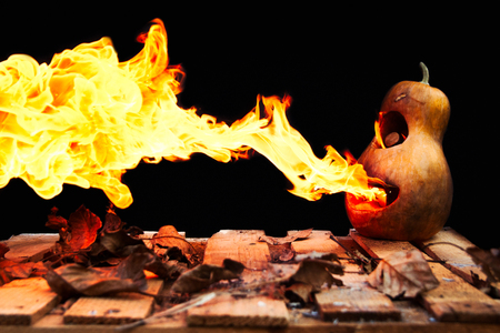 Halloween pumpkin minion spewing flames of fire on a black backgroundの写真素材
