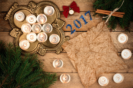 Christmas background with fir branches and candles, small clocks, paper and parchment sheet...