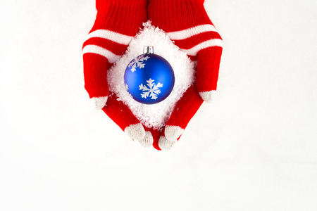 Christmas card, gloves on hands holding blue  ball with snowflakes isolated on a white background with space for textの写真素材
