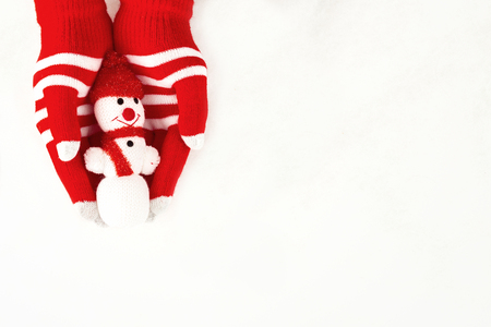 Christmas card, gloves on hands holding a snowman isolated on a white background with space for textの写真素材