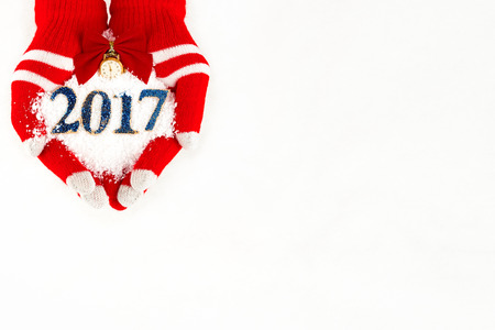 Christmas card, gloves on hands holding snow clock with time  five to midnight and 2017 new year...
