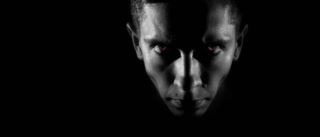 Strict male face in the dark, fiery eyes, a monochrome image, with space for textの写真素材