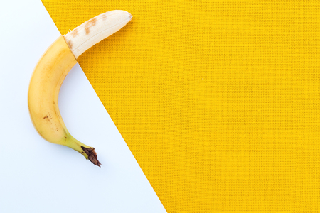Half-cleaved yellow ripe bananas from the tropics on a white and yellow fabric background with space for textの写真素材
