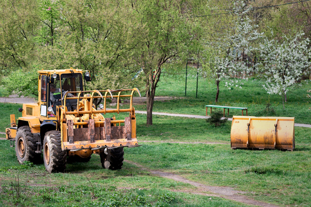 A tractor with a clamp instead of a bucket cleans away garbage, branches, waste