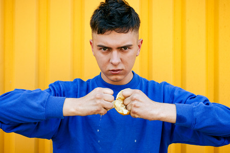Stylish serious guy in a blue sweater tears a lemonの写真素材
