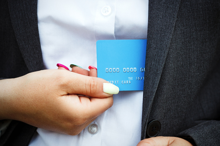 Concept of purchases, banking services. A woman in a suit and glasses shows a credit card from a suit. With a place for advertising text.の写真素材