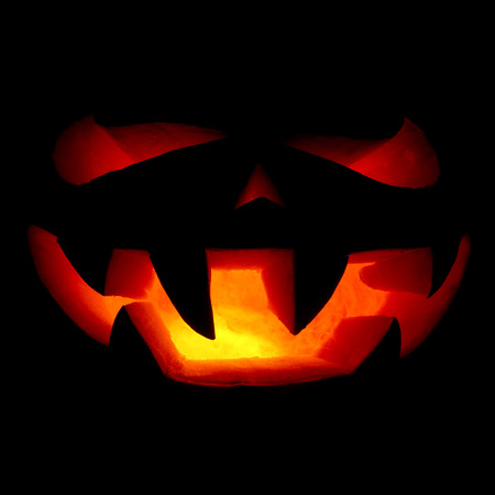 A very terrible Halloween pumpkin, with a terrible look and a smirk of a villain, in the darkの写真素材