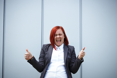 Success! Victory! Happy successful red-haired girl boss, businesswoman in a suit emotionally celebrates, with space for text and advertisingの写真素材