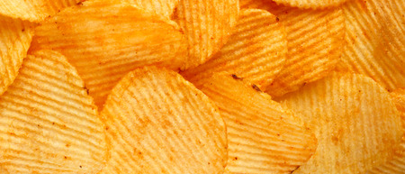 background of crispy golden chips with ribbed texture, seasoned, with sunlight. Frame for wallpapers, background, and texture. wide Horizontalの写真素材