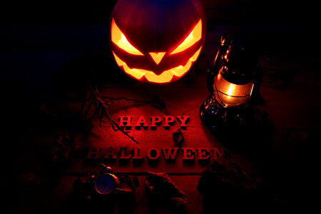 Halloween concept. Background of the holiday mystical pumpkin, jack lantern, bat lamp and many leaves in the dark with the letters Happy Halloweenの写真素材