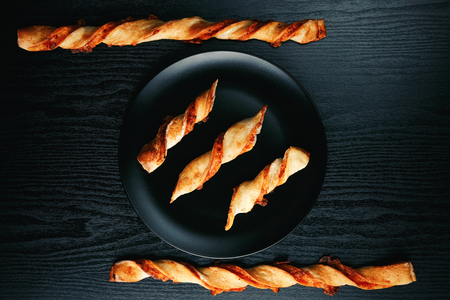 Tasty appetizing cheese sticks on a black plate on a wooden black tableの写真素材