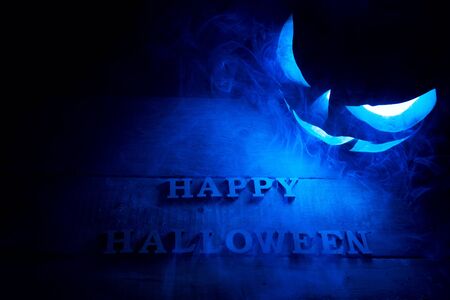Halloween concept. Background of the holiday mystical pumpkin, jack lantern, in the dark with icy blue light and smoke with the letters Trick and Treatの写真素材