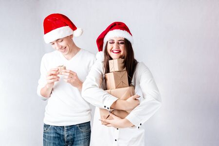 Happy couple man and fat woman celebrate Christmas and new year. Man and woman model plus size in santa hats. Family husband and wife XXL enjoys New Year's giftの写真素材