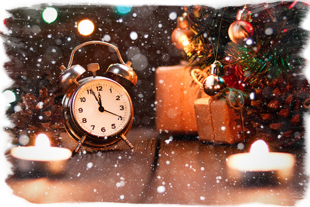 Fairy Christmas composition. Postcard card for the new year. The clock is almost midnight, the countdown. Spruce branches, toy balls with bokeh from garlands, gifts, cones and candles with snow.の写真素材