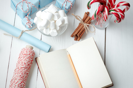 Christmas New Year composition marshmallow candy stick in glass vintage gifts cinnamon thread paper notepad with place for text on white wooden table background banner web designの写真素材