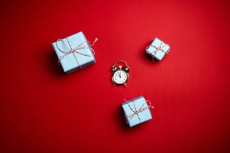 Christmas New Year composition gifts and alarm clock with place for text on red table background banner web designの写真素材