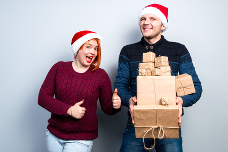 christmas new year happy couple celebrate holiday give gifts emotions man and woman in santa claus hatsの写真素材