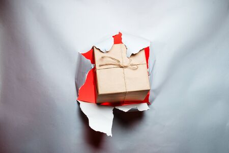 Christmas New Year concept, gift breaks through paper, with place for textの写真素材