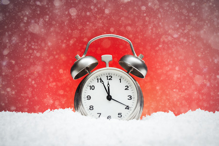 Christmas composition. Greeting card for new year clock Alarm clock on snow on red background with...