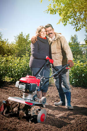 Happy couple of a family of farmers on their garden rejoice on a sunny day after plowing the landの写真素材