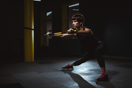 fitness girl doing crossfit exercises in gym with in dark hall, sporty woman sexy in pose doing functional training, poster banner healthy lifestyleの写真素材