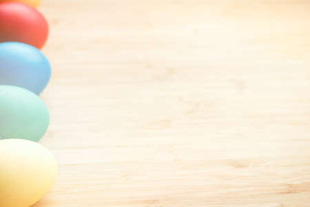 Easter concept painted eggs on wooden table in plate for holiday with place for text pattern with glowの写真素材