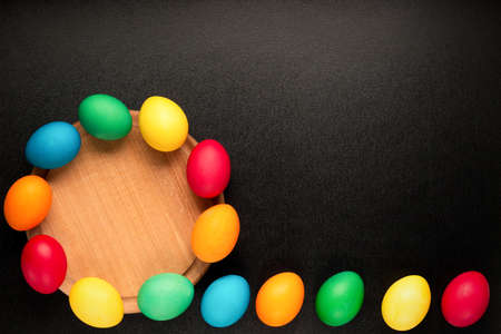 Easter concept painted eggs on black background in row for holiday with place for text with wooden...