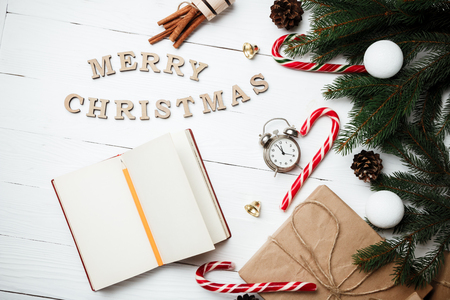 Christmas composition New Year concept clock with xmas gifts sweets toys balls rope cinnamon fir tree marshmallow candle on white wooden table flat lay with space for textの写真素材