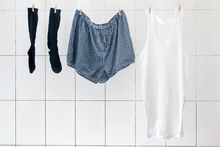 Men's briefs socks and shirts weigh in the bathroom on the rope to dry. Linen for every day of the week, linens for every day, bachelor panties, family pantiesの写真素材