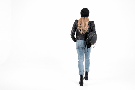 Sexy hipster woman in jacket, jeans stand on white background with place for text. gorgeous girl in boots and hat with bagの写真素材