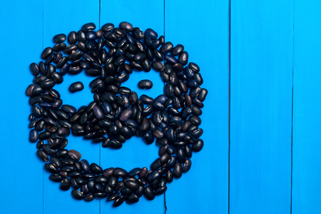 Big Black bean grain, bean pod, a lot of beans texture pattern background for web design and sale. bean in form of smile on blue wooden backgroundの写真素材