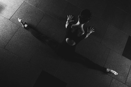 fitness girl doing split exercises in gym yoga pose in dark hall, sporty woman sexy  doing functional training, poster banner healthy lifestyleの写真素材