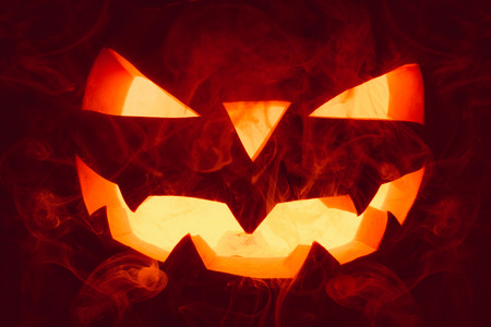 Very terrible Halloween pumpkin, with a terrible look and a smirk of a villain, in the dark with smokeの写真素材