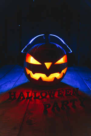 Concept of Halloween. Pumpkin jack Lamp, in headphones with CDs in teeth and the inscription Halloween party with warm and cold light, poster for the partyの写真素材