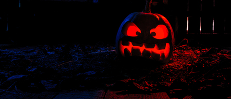 Halloween - pumpkins and candles in an abandoned wooden house on leaves and wooden boards with a...