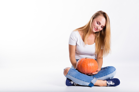 Halloween concept, happy Girl sitting on floor with pumpkins preparing for holiday, Jack lantern, funny and spooky pumpkin. Trick or treat tradition.の写真素材