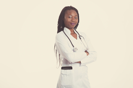 Female american african doctor, nurse woman wearing medical coat with stethoscope and tablet in poket. Happy excited for success medical worker posing on light backgroundの写真素材