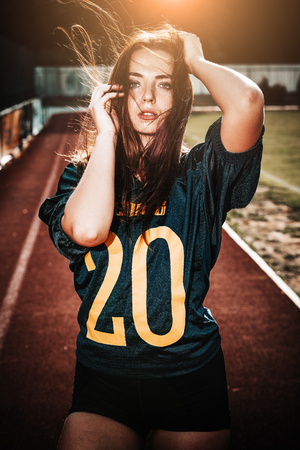 Sexy young sportive girls in t-shirt of rugby football player in action on the stadium. American...