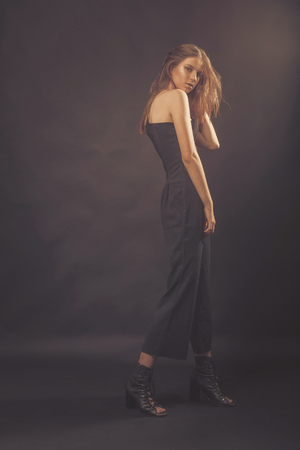 Fashionable girl in golden gray tones in studio. Woman with unflappable face. Lifestyle concept in fashion worldの写真素材