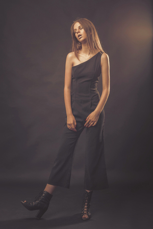 Fashionable girl in golden gray tones in studio. Woman with unflappable face. Lifestyle concept in fashion worldの写真素材