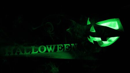 Halloween concept. An ominous pumpkin with Halloween inscription, with a cold blue glow and smoke, a poster for a partyの写真素材