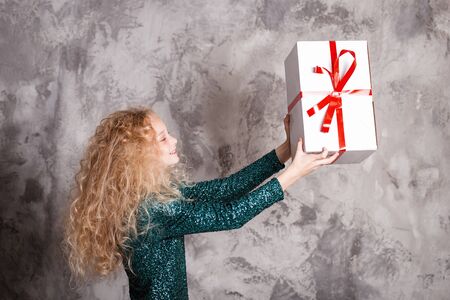 Merry Christmas and happy new year! happy girl with big present in hands looks very pleased. Close portraitの写真素材