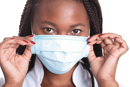 Female american african doctor, nurse woman wearing medical coat with stethoscope and mask. Happy excited for success medical worker posing on light backgroundの写真素材