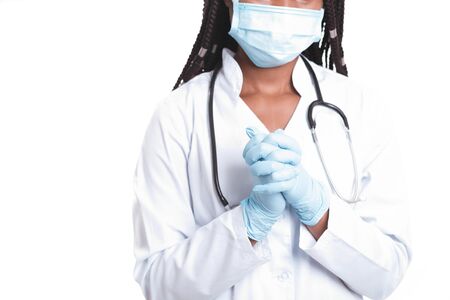 Female american african doctor, nurse woman wearing medical coat with stethoscope, mask and gloves. Happy excited for success medical worker posing on light backgroundの写真素材