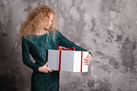 Merry Christmas and happy new year! happy girl with big present in hands thinking about giftの写真素材