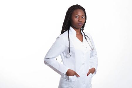 Serious Female american african doctor, nurse woman wearing medical coat with stethoscope. Happy excited for success medical worker posing on light background isolatedの写真素材