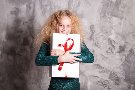 Merry Christmas and happy new year! happy girl with big present in hands looks very pleased. Close portraitの写真素材